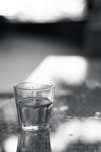 Et glas vand fyldt halvvejs, fotograferet i sort-hvid